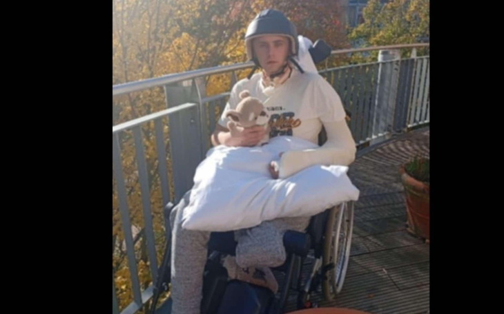 Młody mężczyzna w wózku inwalidzkim, trzymający pluszaka.