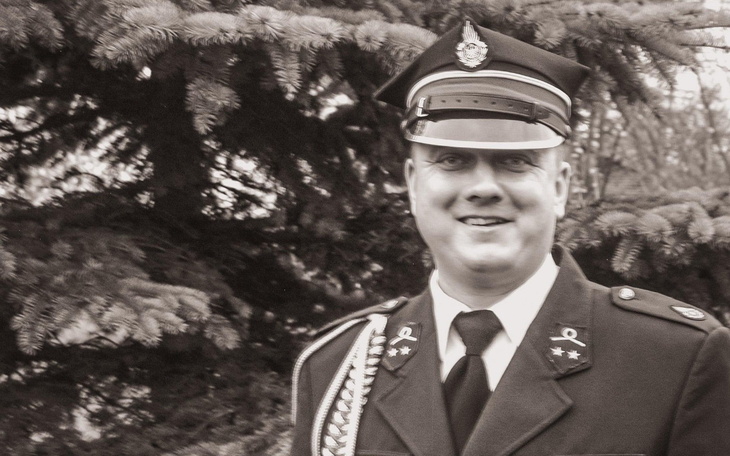 Mężczyzna w mundurze, uśmiechający się do kamery.