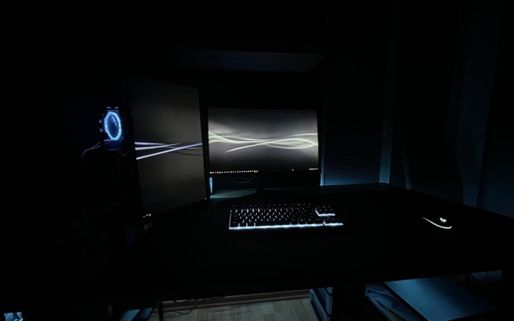 Ciemne biurko z komputerem w ciemnym pomieszczeniu.
