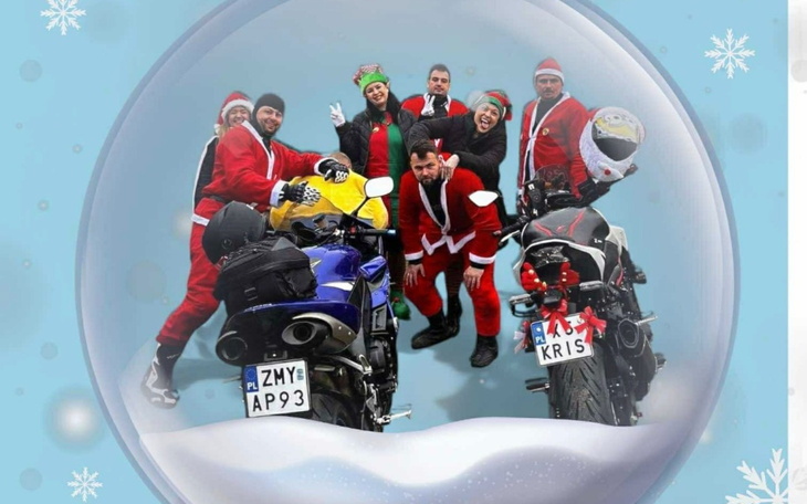 Grupa osób w strojach świątecznych z motocyklami w tle.
