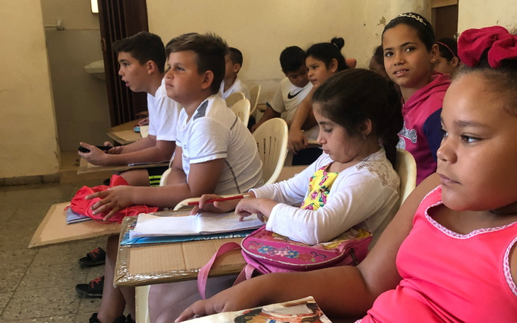 Dzieci siedzące w klasie, skupione na zajęciach.