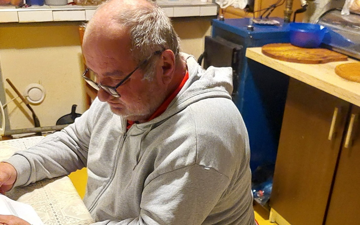 Mężczyzna czytający dokumenty w kuchni.