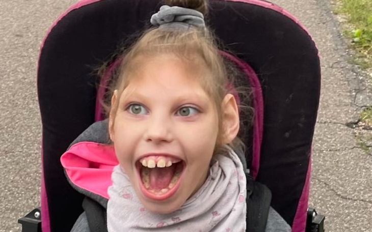 Dziewczynka w wózku, uśmiechnięta, z zębami na wierzchu.