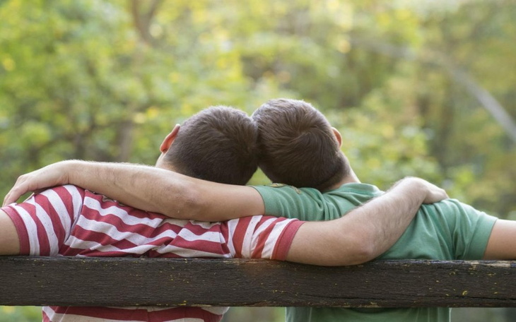 Dwie osoby siedzące na ławce, przytulające się w parku.