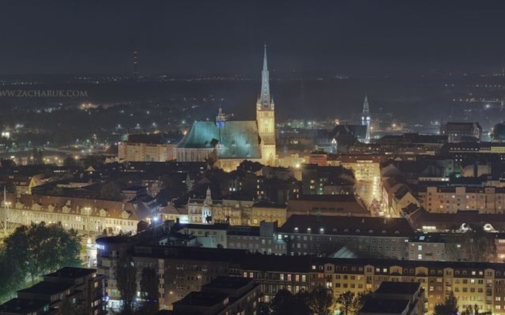 Widok na miasto nocą, z oświetlonymi budynkami.