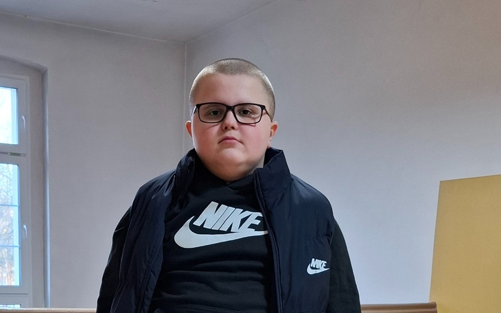 Chłopiec w okularach, ubrany w czarną kurtkę i bluzę.