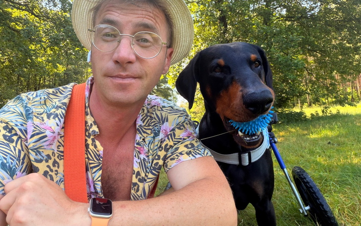 Selfie mężczyzny z psem do wizyty w parku, w tle las i słońce.