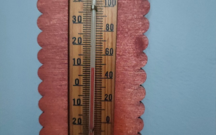 Termometr drewniany na ścianie, wskazujący temperaturę.