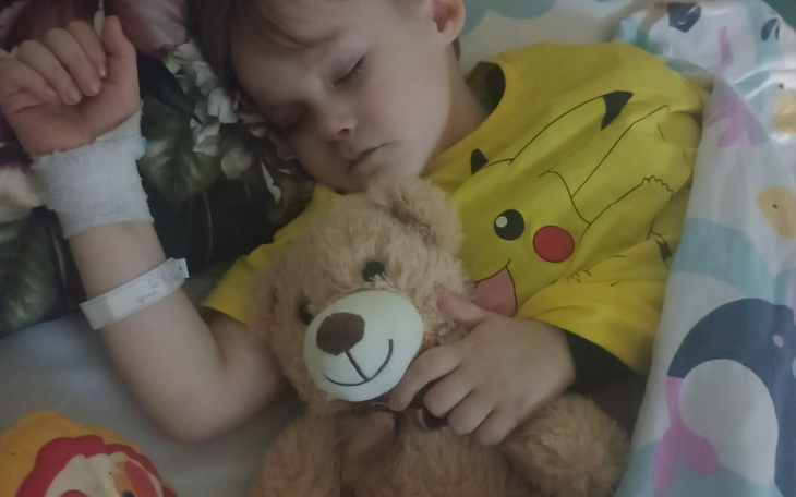 Dziecko śpiące z pluszowym misiem, w kolorowej pościeli.