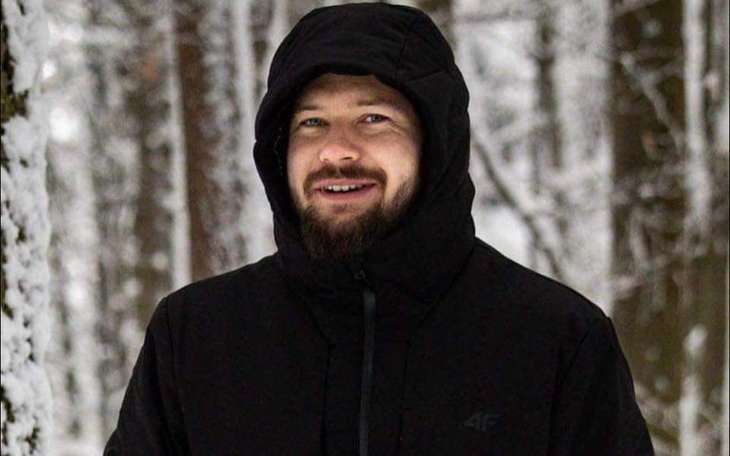 Mężczyzna w czarnej kurtce na tle zimowego lasu.