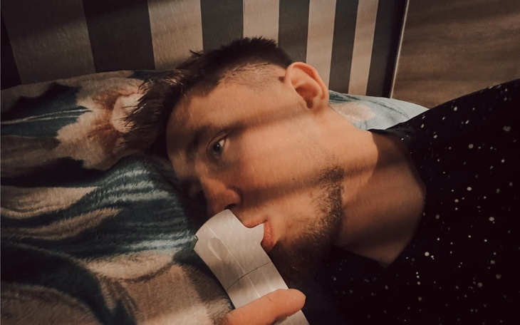 Mężczyzna leżący na łóżku z telefonem.