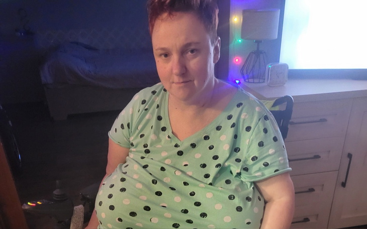 Kobieta w koszulce w kropki, siedząca w wózku inwalidzkim.