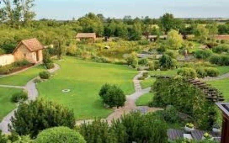 Widok na zadbany ogród z alejkami i roślinnością.