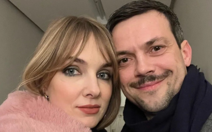 Para uśmiechająca się do kamery w przytulnym otoczeniu.