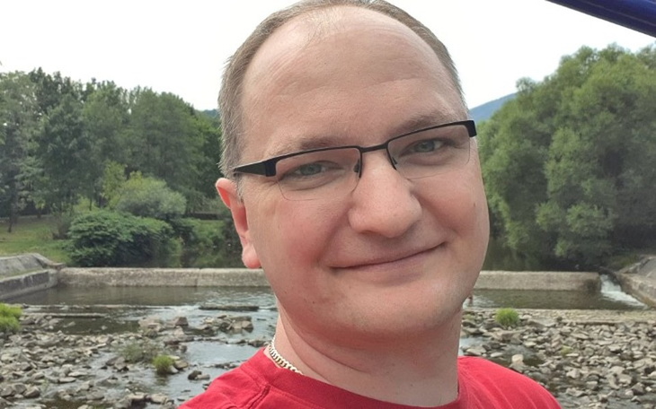 Mężczyzna uśmiechający się na tle rzeki.