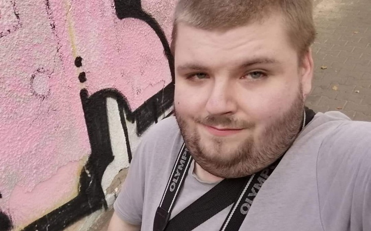 Mężczyzna pozujący na tle kolorowej ściany z graffiti.