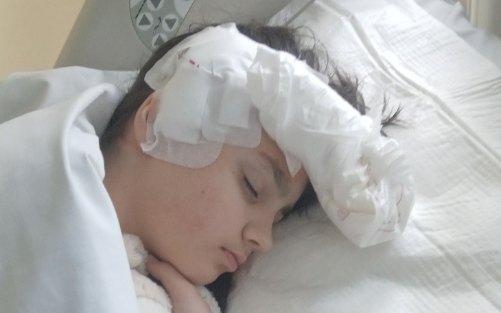 Dziecko śpiące w szpitalu z opatrunkiem na głowie.