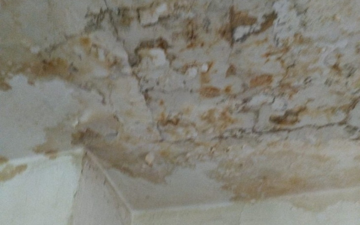 Zniszczony sufit z widocznymi plamami i uszkodzeniami.