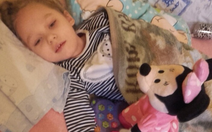 Mała dziewczynka w łóżku z pluszowym misiem.