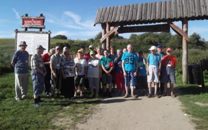 Grupa ludzi na szlaku turystycznym w słoneczny dzień.