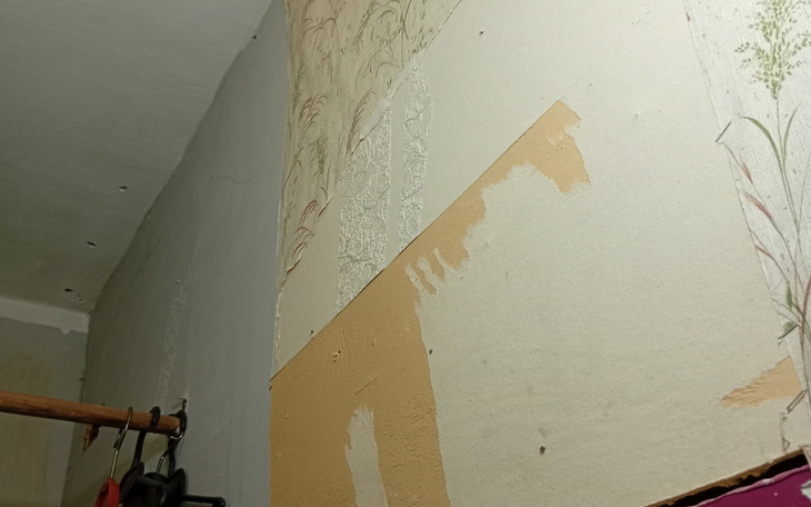 Fragment ściany z odklejoną tapetą.