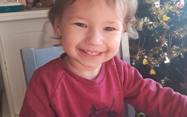 Uśmiechnięte dziecko siedzące przy stole w domu.