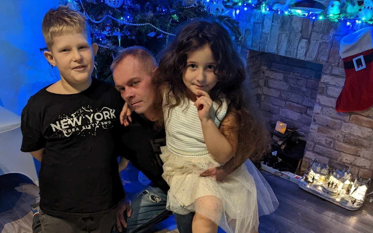 Dzieci z dorosłym przy choince, w świątecznym nastroju.