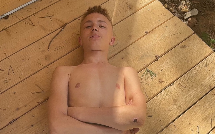 Młody chłopak leżący na drewnianym tarasie, z rękami skrzyżowanymi.