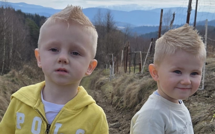 Dwóch małych chłopców na ścieżce, z uśmiechami na twarzach.