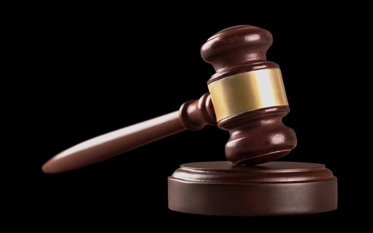 Młotek sędziowski na czarnym tle, symbolizujący sprawiedliwość.