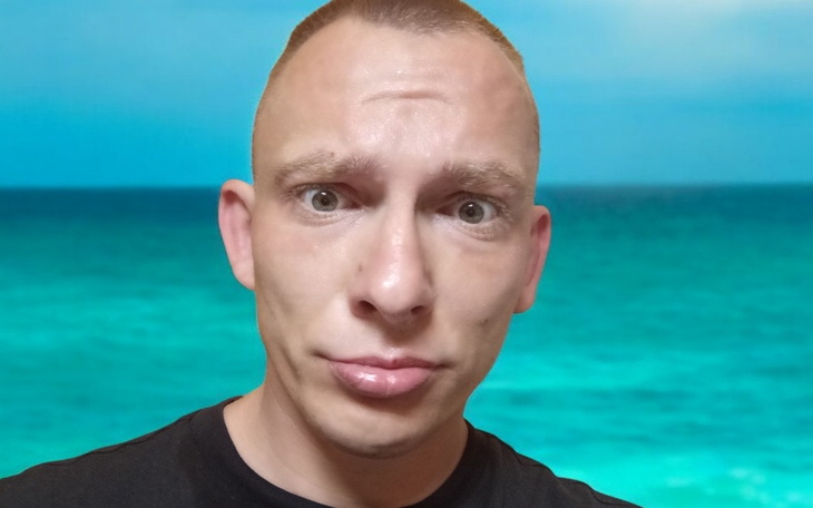 Mężczyzna z zaskoczoną miną, w tle morze.