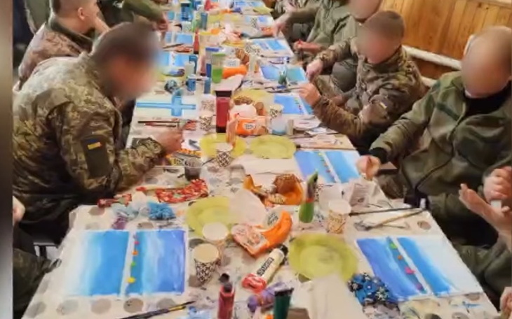 Grupa żołnierzy maluje obrazy przy stole.