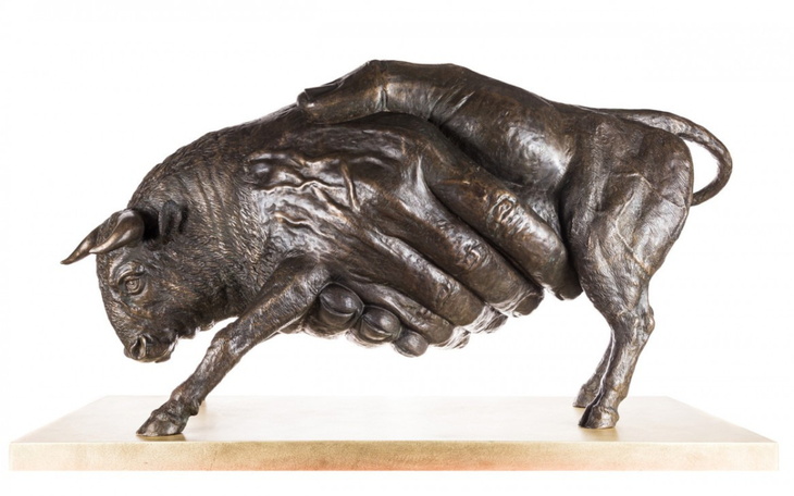 Rzeźba przedstawiająca byka trzymanego przez dłoń.