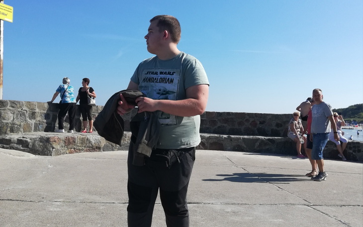 Młody mężczyzna na plaży, w letnim otoczeniu.