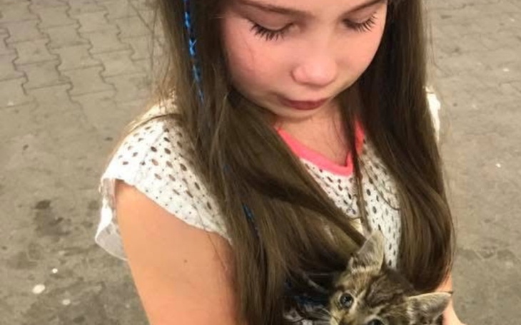 Dziewczynka trzymająca kota, uśmiechając się do obiektywu.