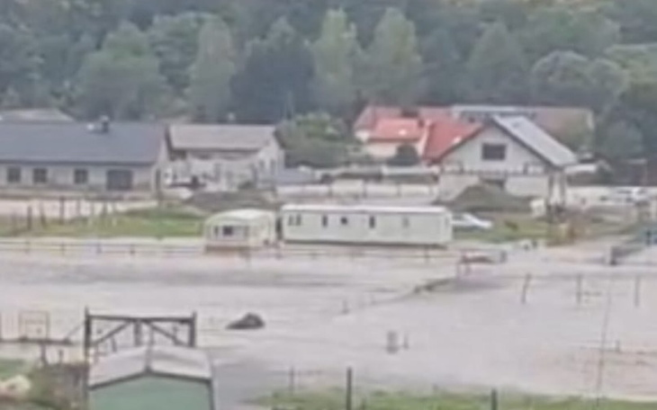 Widok na teren z zalanym obszarem i budynkami.