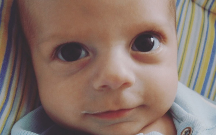 Uroczy niemowlak z dużymi oczami i delikatnym uśmiechem.