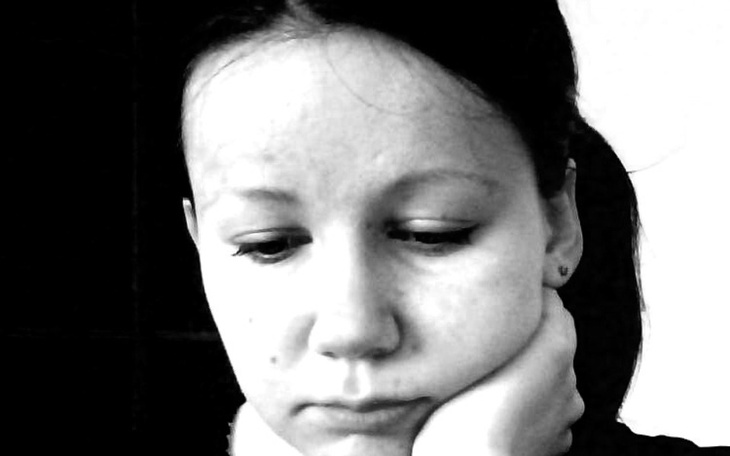 Refleksyjna kobieta w czarno-białym ujęciu, z zamyśloną miną.