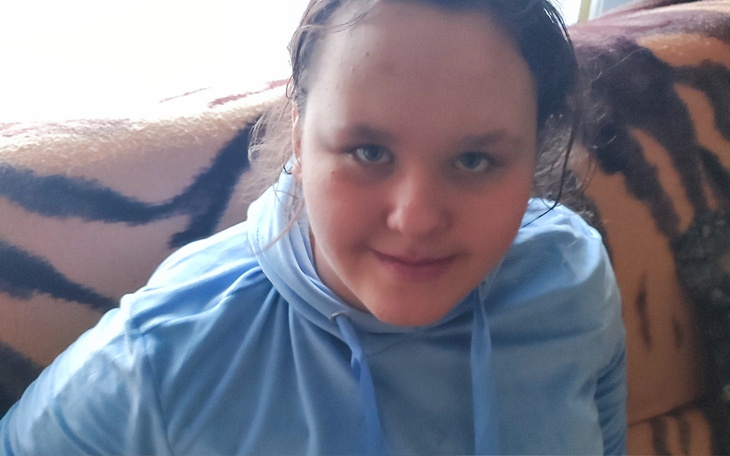 Młoda kobieta z uśmiechem, siedząca na kanapie.