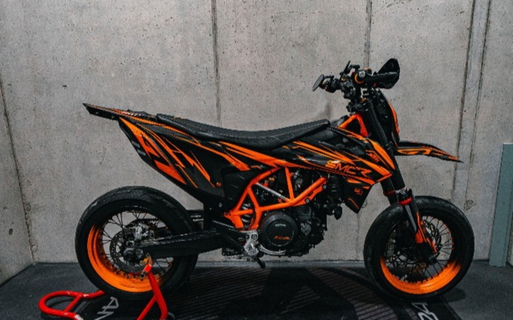 Motocykl w kolorze czarno-pomarańczowym w garażu.