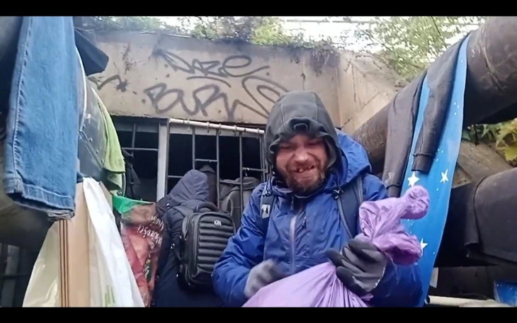 Mężczyzna w niebieskiej kurtce w schronisku, trzymający torbę.