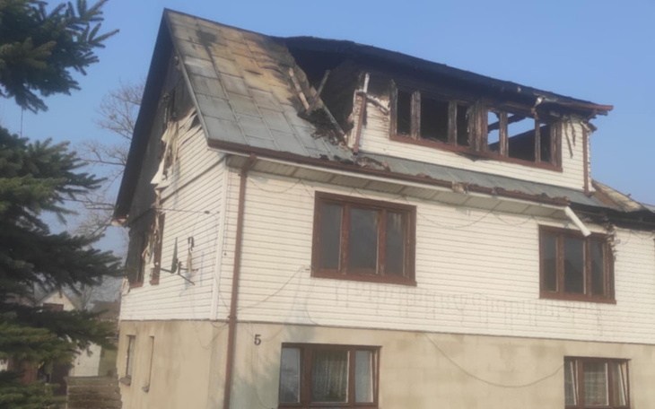 Zniszczony dom po pożarze, z uszkodzoną elewacją i dachem.