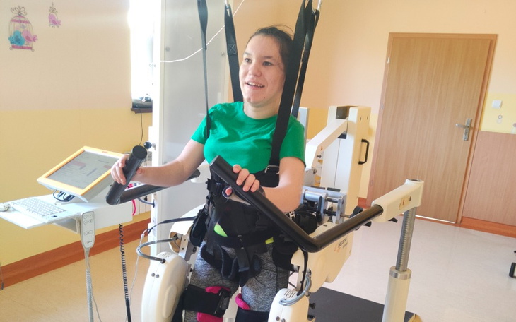 Młoda dziewczyna korzystająca z rehabilitacji w specjalnym urządzeniu.