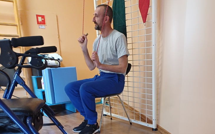 Mężczyzna siedzący na krześle, trzymający liny.