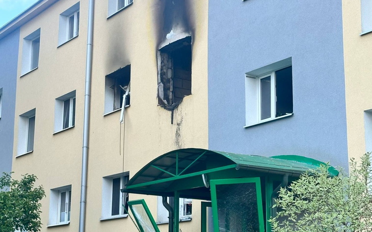 Zniszczone okno budynku po pożarze, widoczne ślady dymu.