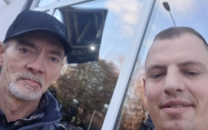 Mężczyźni pozujący do selfie przed szklanym budynkiem.