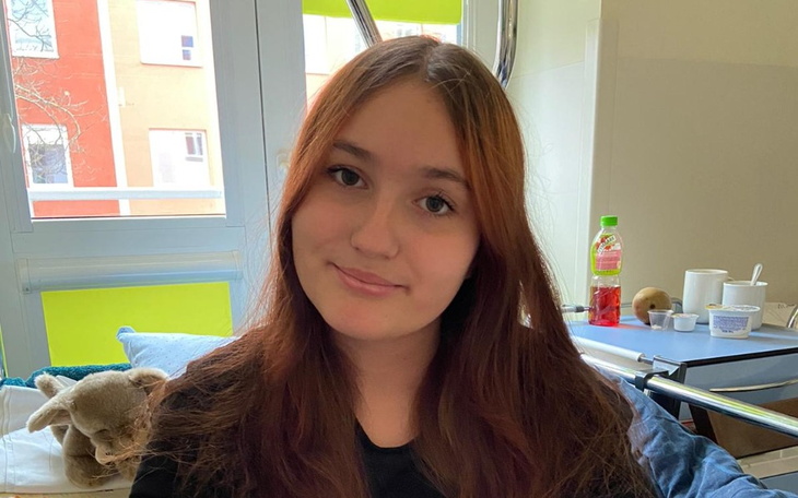 Młoda dziewczyna uśmiechająca się w szpitalnym łóżku.