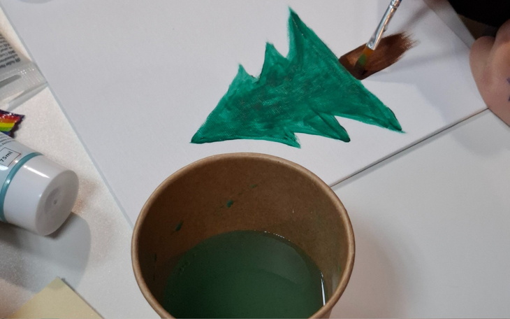 Malowanie choinki, z farbą i kubkiem wody obok.