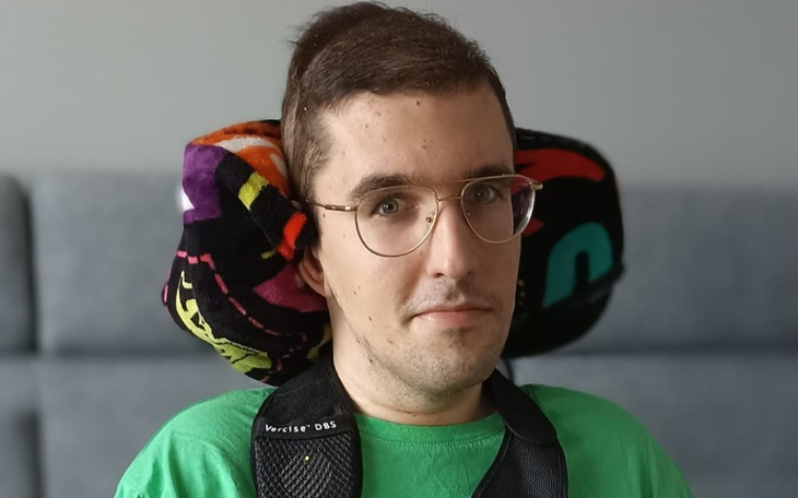 Młody mężczyzna w fotelu, z podparciem na głowie.