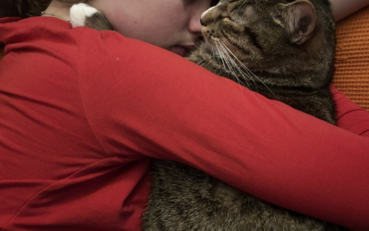 Osoba przytulająca kota, wyrażająca miłość i czułość.